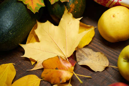 autumn still life in rustic style as a background - leaves, vegetables and fruits, nuts and other...