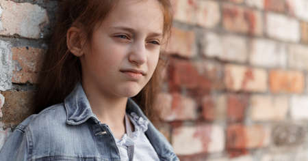 portrait of a beautiful teenage girl posing against a brick wallの写真素材