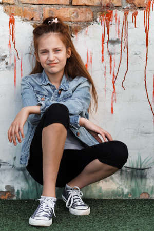 portrait of a beautiful teenage girl posing against a brick wallの写真素材
