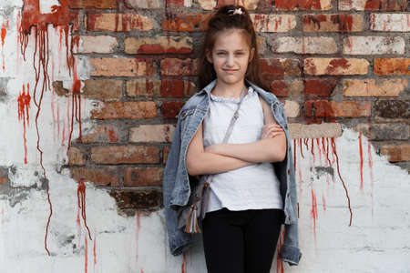 portrait of a beautiful teenage girl posing against a brick wallの写真素材