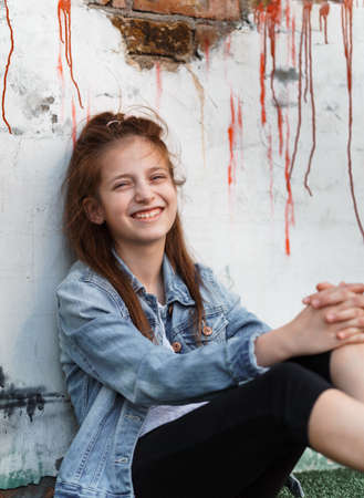 portrait of a beautiful teenage girl posing against a brick wallの写真素材