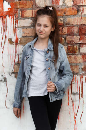 portrait of a beautiful teenage girl posing against a brick wallの写真素材