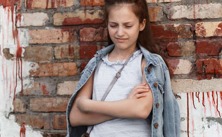 portrait of a beautiful teenage girl posing against a brick wallの写真素材