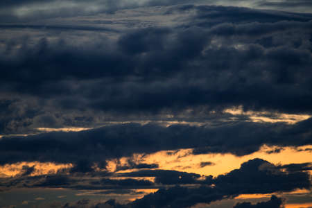beautiful sunset sky, bright sun and dark silhouette of clouds as a background
