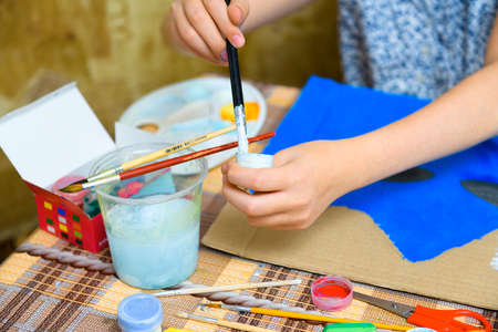 a girl drawing blue gouache cardboard, artistic creation at home, makes creative artwork