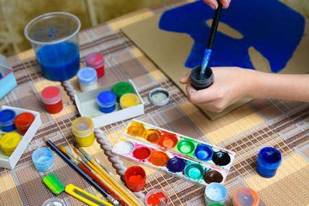 a girl drawing blue gouache cardboard, artistic creation at home, makes creative artwork