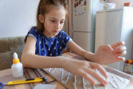 the girl draws blue gouache cardboard, makes a abstract background, sits in the home kitchen