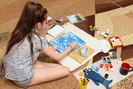 girl draws at home, artistic creation, makes creative artwork from paper, paints and brushes