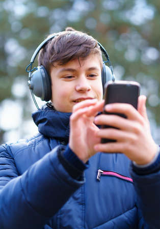 teenager listening to music in headphones, relaxing outdoor, walks in autumn city park, beautiful natureの写真素材