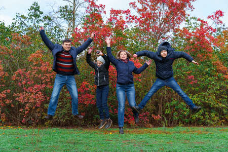 family jumping in autumn city park, happy people together, parents and children, beautiful nature with colorful leavesの写真素材