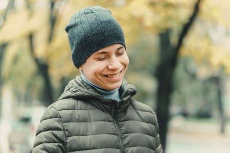 portrait of a teenager boy with umbrella, autumn season, city street