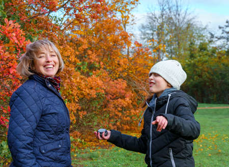 mother and daughter playing and having fun in autumn park, happy people together, parent and...
