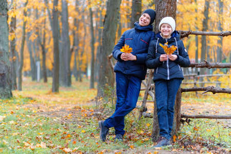 teen girl and boy walking through the park and enjoys autumn, beautiful nature with yellow leavesの写真素材