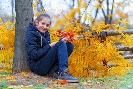 a girl posing and enjoying autumn in city park, beautiful nature with yellow leavesの写真素材