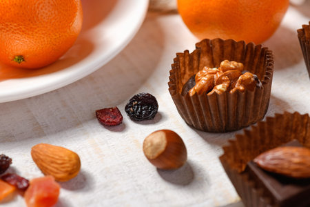 sweet food background for christmas or holiday decoration - chocolate candies, tangerines, nuts and...
