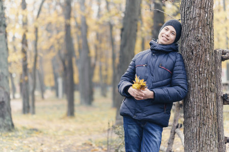 a boy running through the park and enjoys autumn, beautiful nature with yellow leavesの写真素材