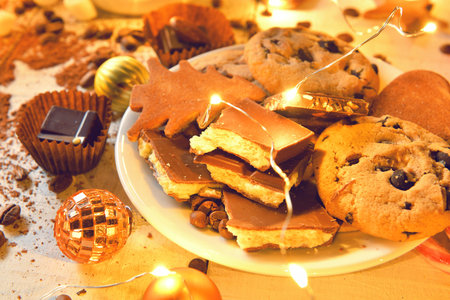 sweet food and decoration background for merry christmas or new year holiday with night illumination - chocolate candies, tangerines, cookies, marshmallow and cocoa latte on white woodの写真素材