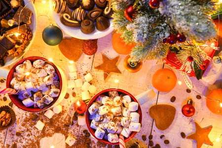 sweet food top view background for merry christmas or new year holiday decoration with night illumination - chocolate candies, tangerines, cookies, marshmallow and cocoa latte on white woodの写真素材