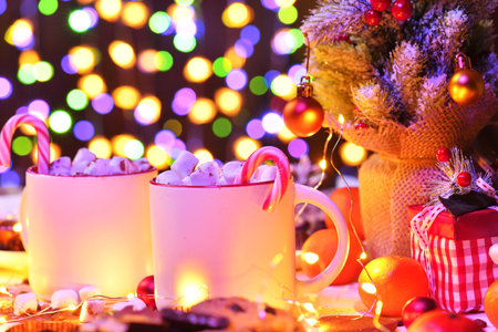 sweet food and decoration background for merry christmas or new year holiday with night illumination - chocolate candies, tangerines, cookies, marshmallow and cocoa latte on white woodの写真素材