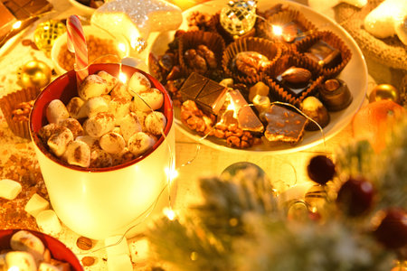 sweet food top view background for merry christmas or new year holiday decoration with night illumination - chocolate candies, tangerines, cookies, marshmallow and cocoa latte on white woodの写真素材