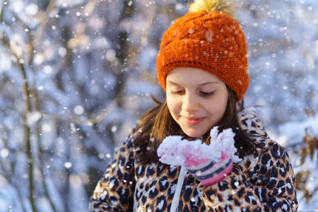 child girl eats snow and having fun in the winter forest, bright sunlight and shadows on the snow, beautiful nature.の写真素材