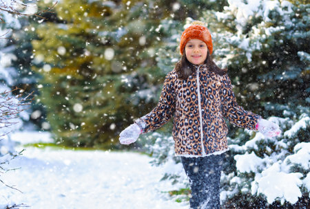 child girl running and playing with snow in the winter forest, bright snowy fir trees, beautiful...