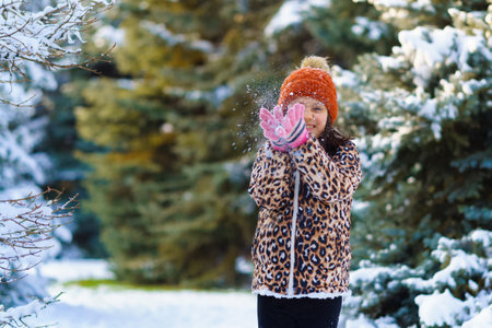 child girl throws up snow and playing in the winter forest, bright snowy fir trees, beautiful nature.の写真素材
