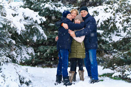 family portrait in the winter forest, parent and children, beautiful nature with bright snowy fir treesの写真素材