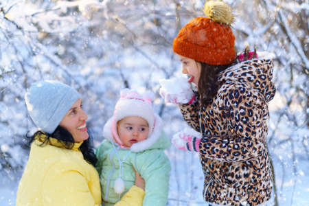 family portrait in the winter forest, mother and children, bright sunlight and shadows on the snow, beautiful nature.の写真素材