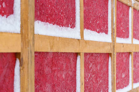 wooden wall in German or Scandinavian style covered snow in winter - the yellow wooden planks is on red wood background, new and clean surfaceの写真素材