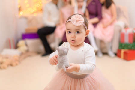 family portrait of a parents and children, dressed in santa helper hat, sitting on a couch in home interior decorated with christmas lights and new year holiday giftsの写真素材