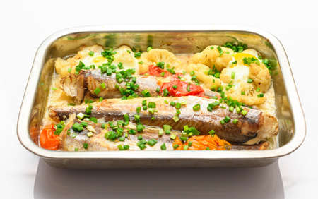 hake fish baked with vegetables close view, baking tray with tomatoes, broccoli and spices, home cookingの写真素材