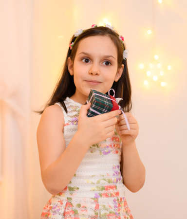 portrait of a child girl in home interior decorated with lights and holiday giftsの写真素材