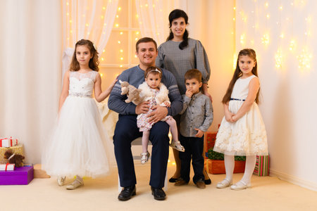 family portrait - parents and children in home interior decorated with holiday lights and giftsの写真素材