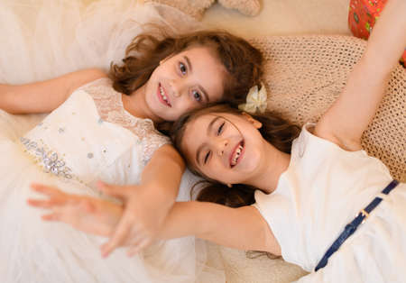 girls is lying on the floor and talking or sleeping, and cover themselves with a blanket, home interior decorated with holiday lights and giftsの写真素材