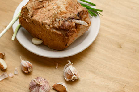 baked meat on a plate, green onion and garlic on wooden background, home cookingの写真素材