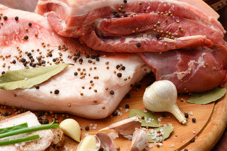 raw pork meat and lard with salt, spices and garlic on a cutting board, dark wooden backgroundの写真素材