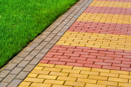 walkway made of paving slabs and green grass as a background, bright sunlightの写真素材