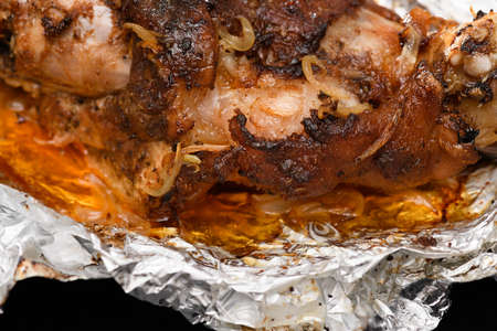 baked meat and fried onions on a baking sheet, pork ham on foil and wooden background, home cookingの写真素材