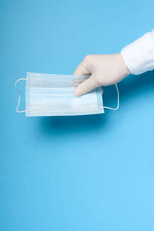 hands in medical gloves with a medical breathing mask on a blue background, health care prevention...