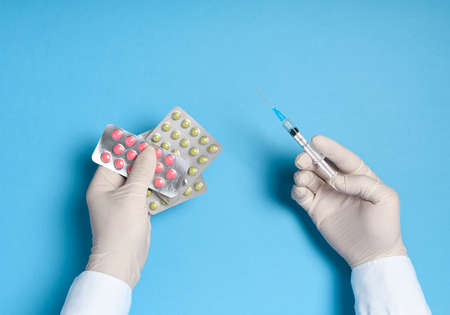 hands in medical gloves with a syringe on a blue background, health care prevention of coronavirus infection, as well as other viruses and pollutionの写真素材