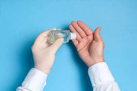 hand sanitizer treatment, health care prevention of virus infection, hands in medical gloves on a blue backgroundの写真素材