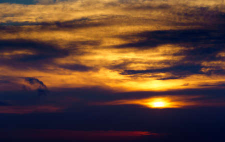 beautiful sunset sky, bright sun and dark silhouette of clouds as a background
