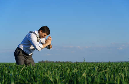 businessman posing in a field, he goes in for sports and does strikes like martial arts, green grass and blue sky as backgroundの写真素材