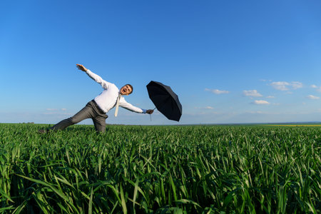 businessman poses with a spyglass, he looks into the distance and looks for something, green grass and blue sky as backgroundの写真素材
