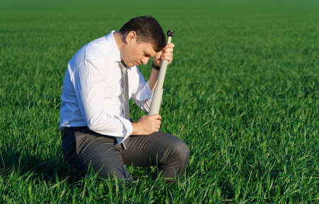 businessman poses with a spyglass in a green field, he looks an idea or something, business concept, green grass and blue sky as backgroundの写真素材