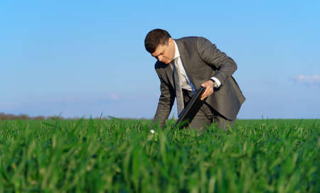 businessman works in a green field, freelance and business concept, green grass and blue sky as backgroundの写真素材