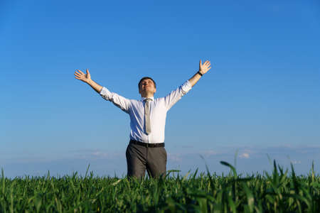 businessman sits in an office chair in a field and rests, freelance and business concept, green grass and blue sky as backgroundの写真素材