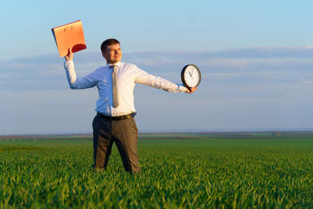 businessman poses with soccer ball in a green grass field - freelance, sport and business concept