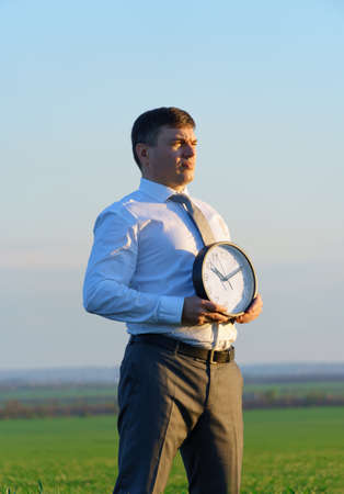 businessman holds a blackboard with an empty space and poses on a green grass field - business...